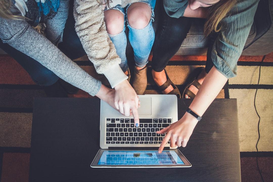 A trio of women pointing at a computer screen.