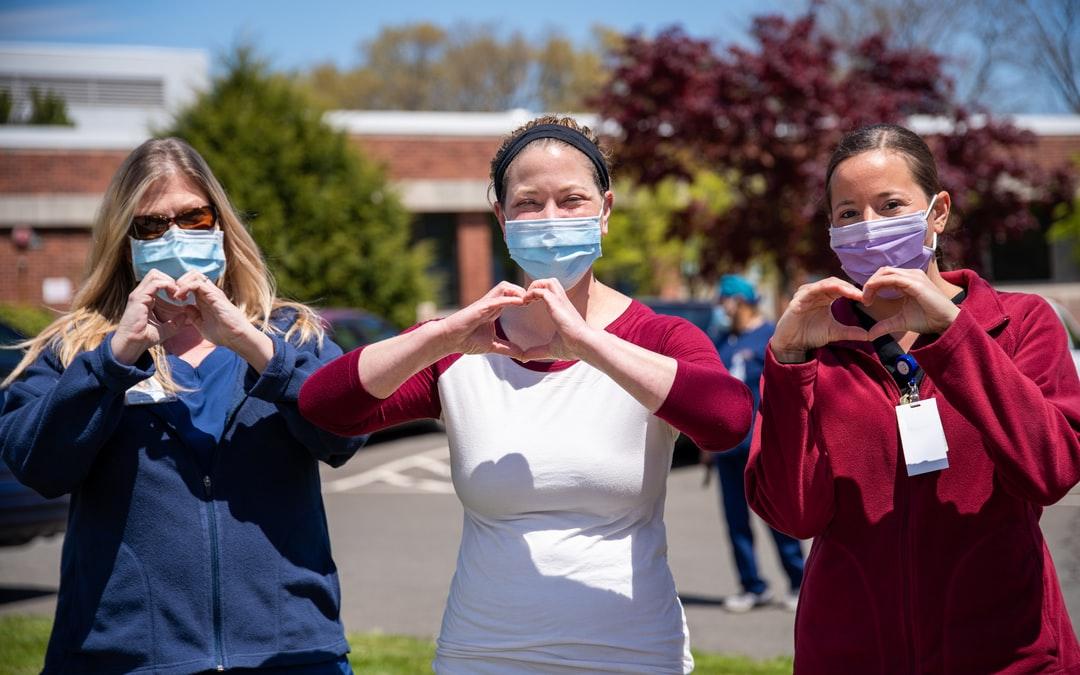 Three nurses making hearts with their hands.