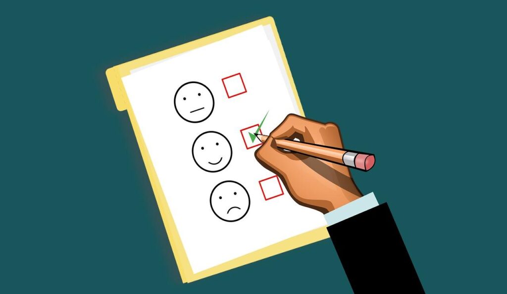 A hand checking the middle of three boxes on a white survey form with different mood faces, representing an employee survey tool.
