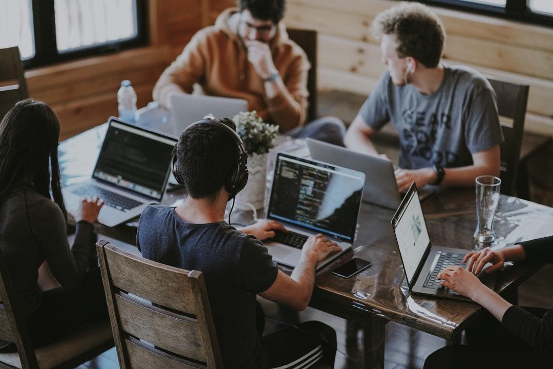 A group of people sitting at a table with their computers.